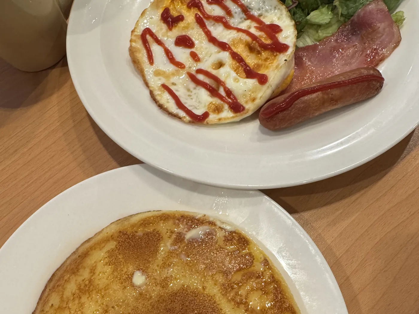 Gusto 的早餐。盘子里有煎蛋、培根、香肠和沙拉,前面的盘子里有松饼。