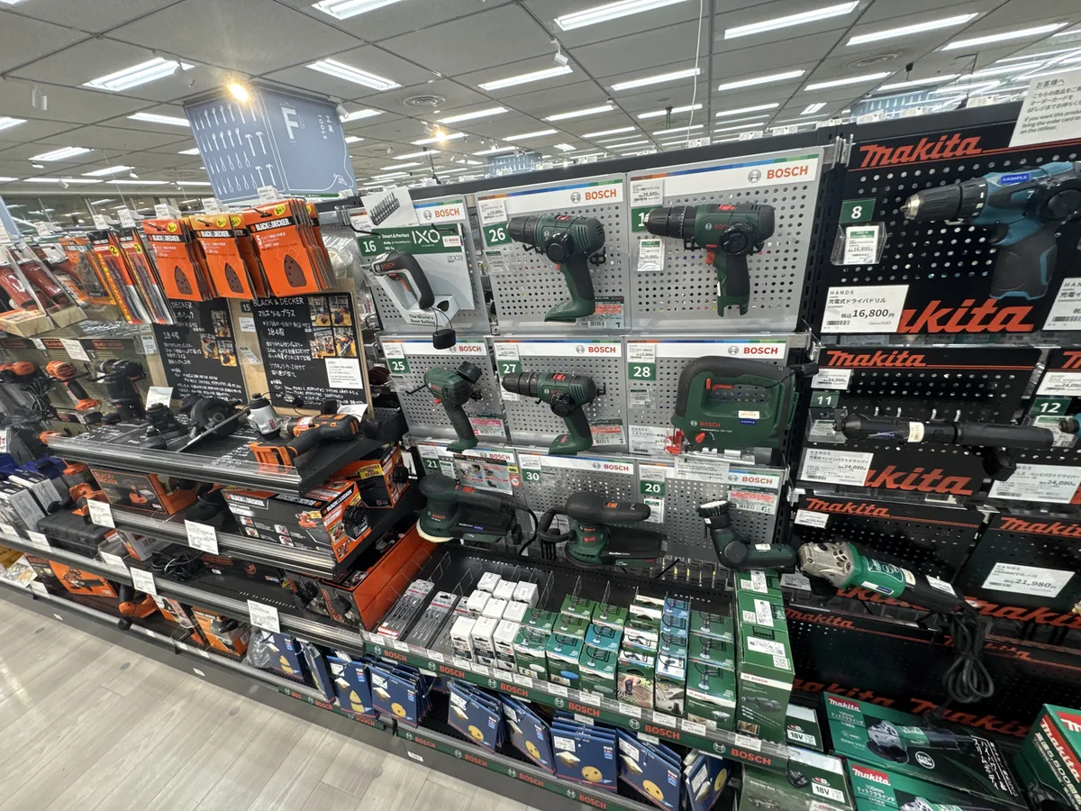 Uno scaffale di elettroutensili. Modelli da esposizione come trapani elettrici sono appesi alla parete, e sugli scaffali sotto sono allineate le scatole.