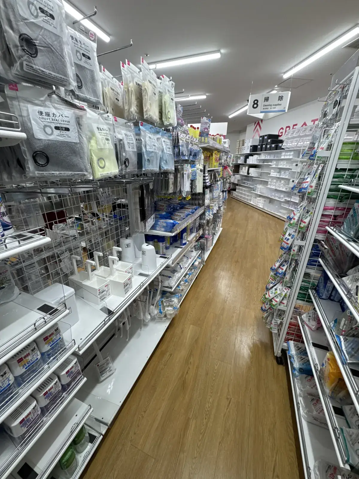 Seksyon ng mga panlinis sa DAISO. Nakasabit sa itaas ng pasilyo ang karatulang "8 掃除 Cleaning supplies" sa Japanese at English.