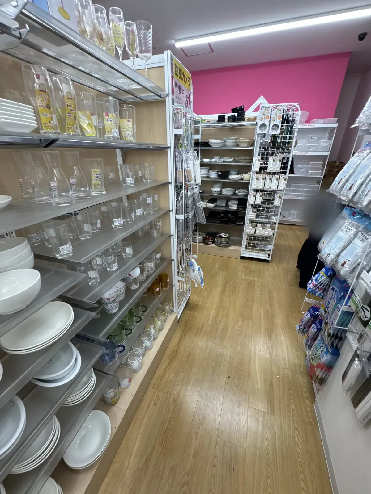 Pasilyo ng seksyon ng mga plato sa DAISO. Sa kaliwang istante ay may mga puting plato, basong salamin, at mangkok ng kanin; sa istante sa dulo ay may mga itim at puting plato.