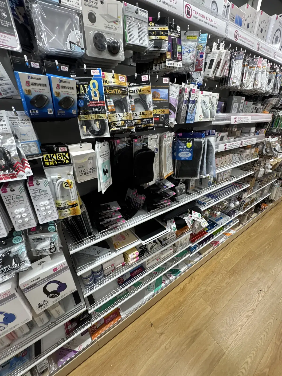Seksyon ng mga cable at accessory ng smartphone. May mga price tag na 300 yen, 500 yen, at 1000 yen ang mga produktong nasa itim na karton.