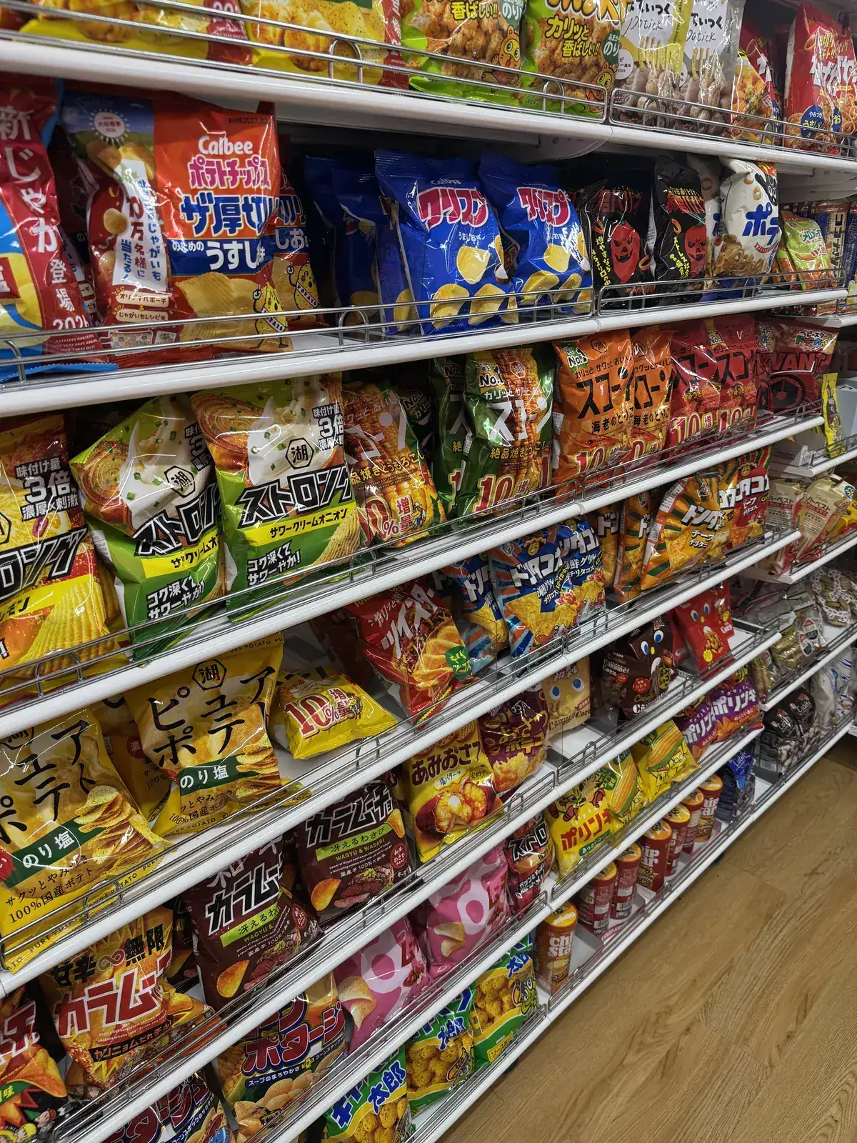 Seksyon ng meryenda sa DAISO. Nakahilera sa ilang palapag ng istante ang maliliit na pakete ng potato chips at iba pang snack.