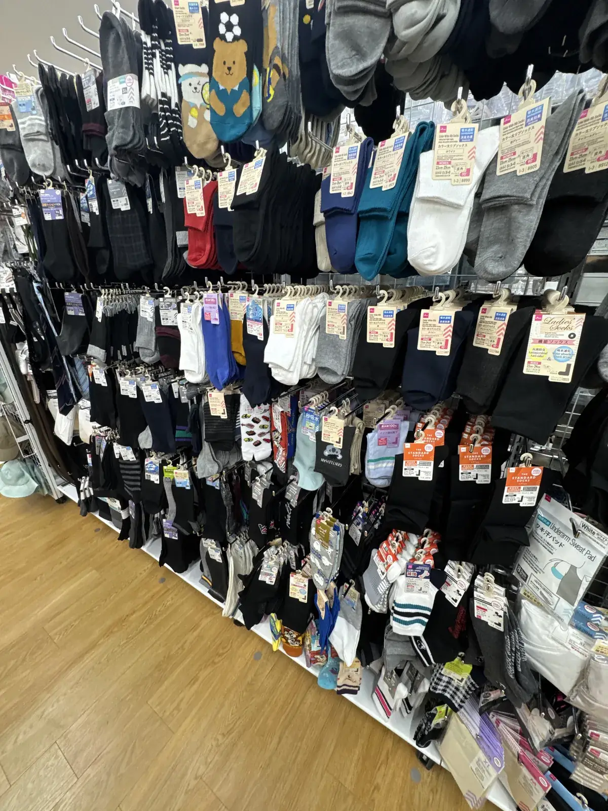 Seksyon ng medyas sa DAISO. Nakasabit sa buong pader ang mga itim, puti, gray, at may-disenyong medyas.