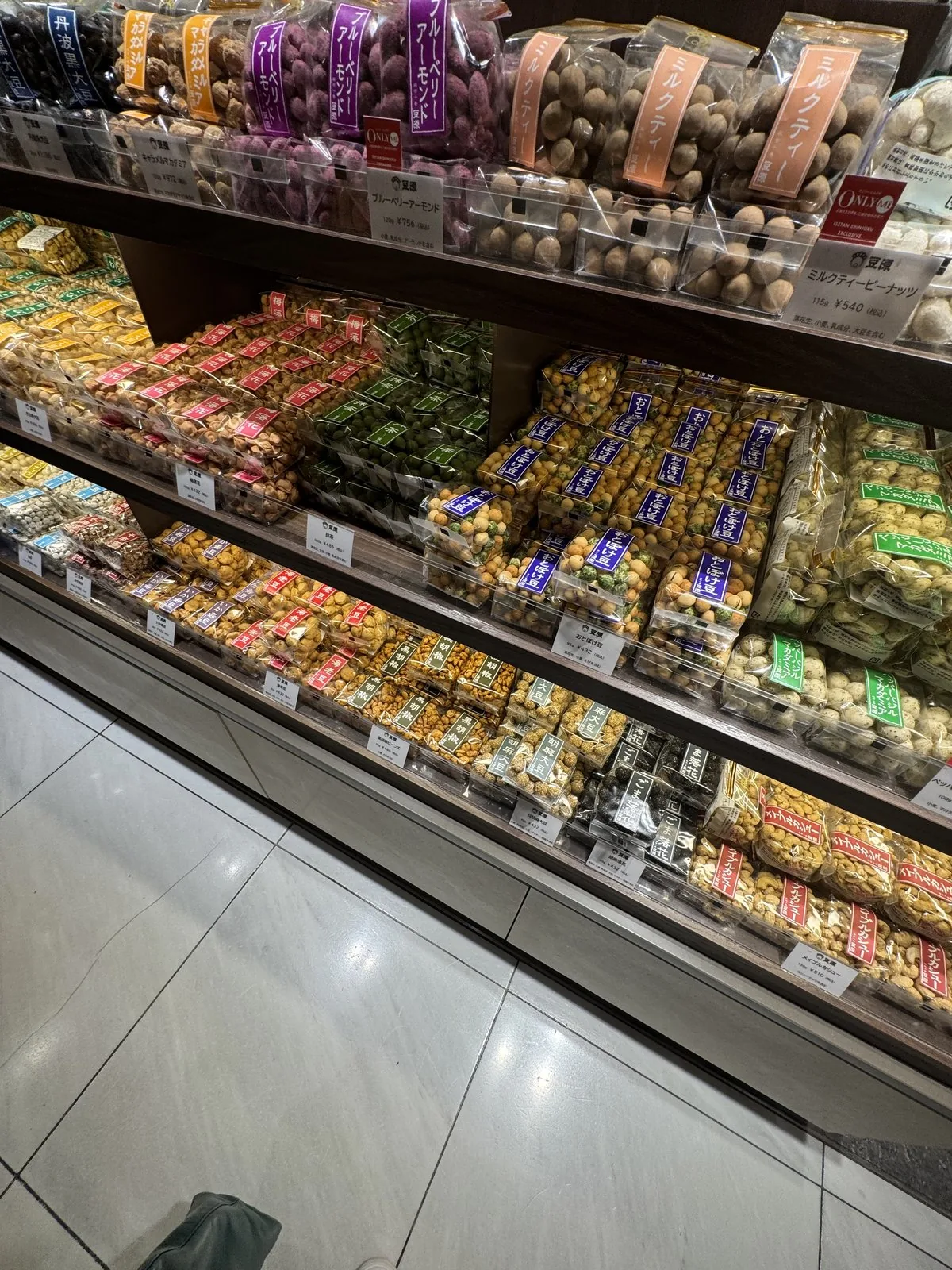 ชั้นวางในพื้นที่ขายขนมชั้น B1F ของอาคารหลัก ขนมบรรจุถุงเรียงแยกตามชนิดและตามสี