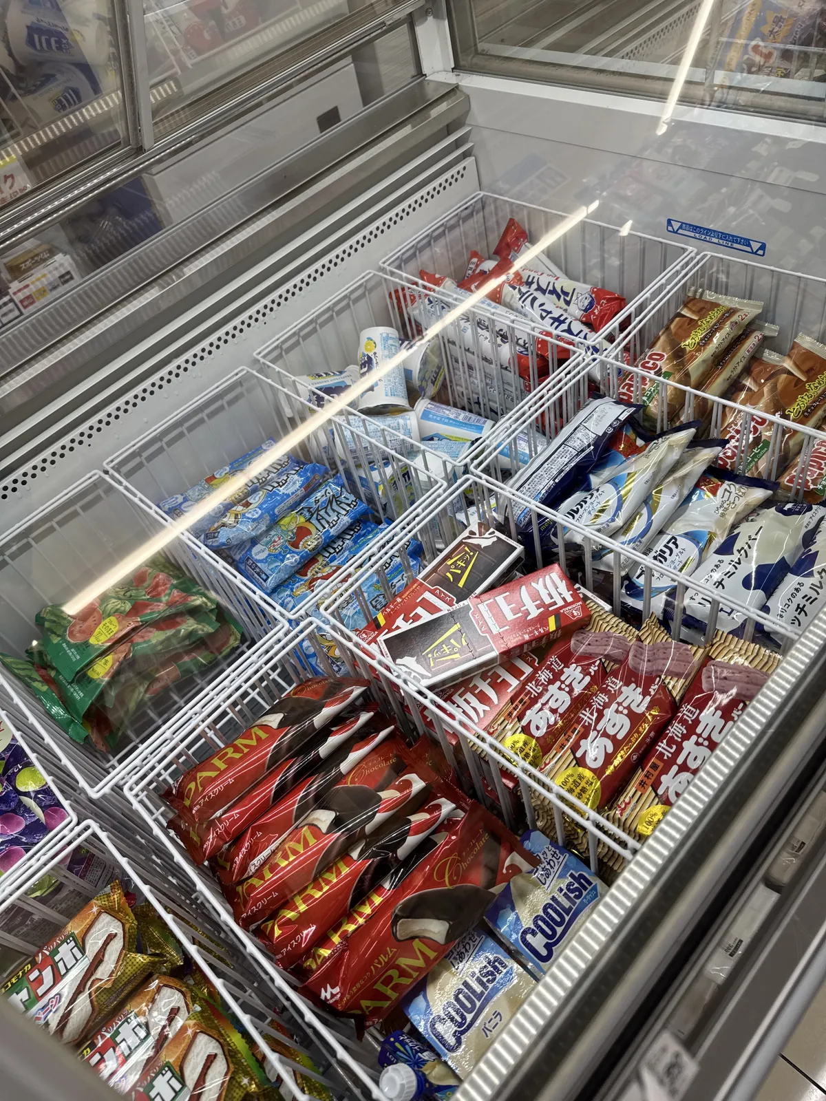 Peti sejuk beku aiskrim di Lawson. Di bawah penutup kaca, aiskrim batang dan aiskrim dalam beg diletakkan dalam bakul jaring dawai mengikut jenis.