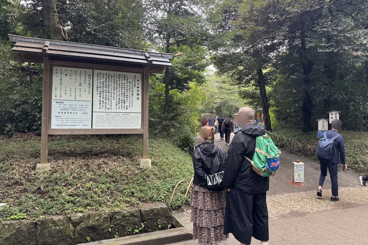 Cartello all'ingresso del giardino Meiji Jingu Gyoen. Gli orari di apertura del giardino e il contributo per la manutenzione sono scritti in giapponese e in inglese. In fondo al sentiero a destra c'è un cartello che indica la direzione del pozzo di Kiyomasa.