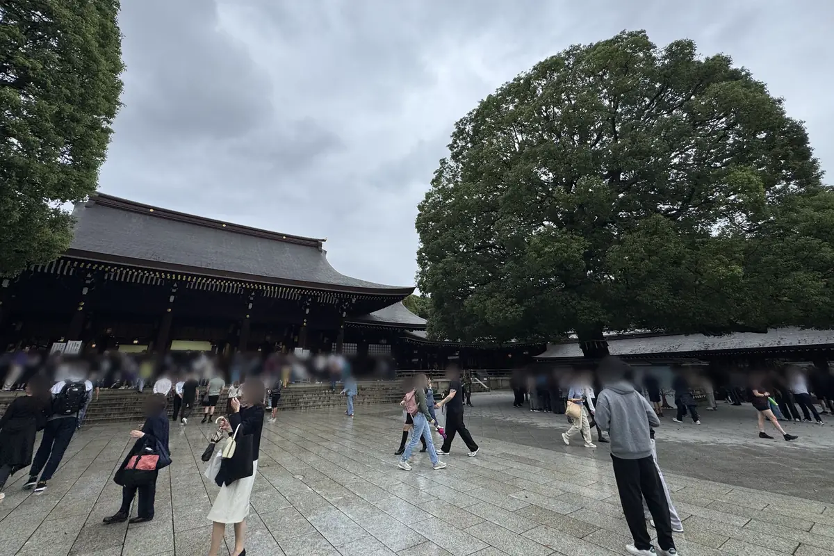 L'edificio principale del Meiji Jingu e, davanti, il piazzale lastricato in pietra. A destra c'è un grande albero di canfora, con la base circondata dalla rastrelliera a cui si appendono le ema.