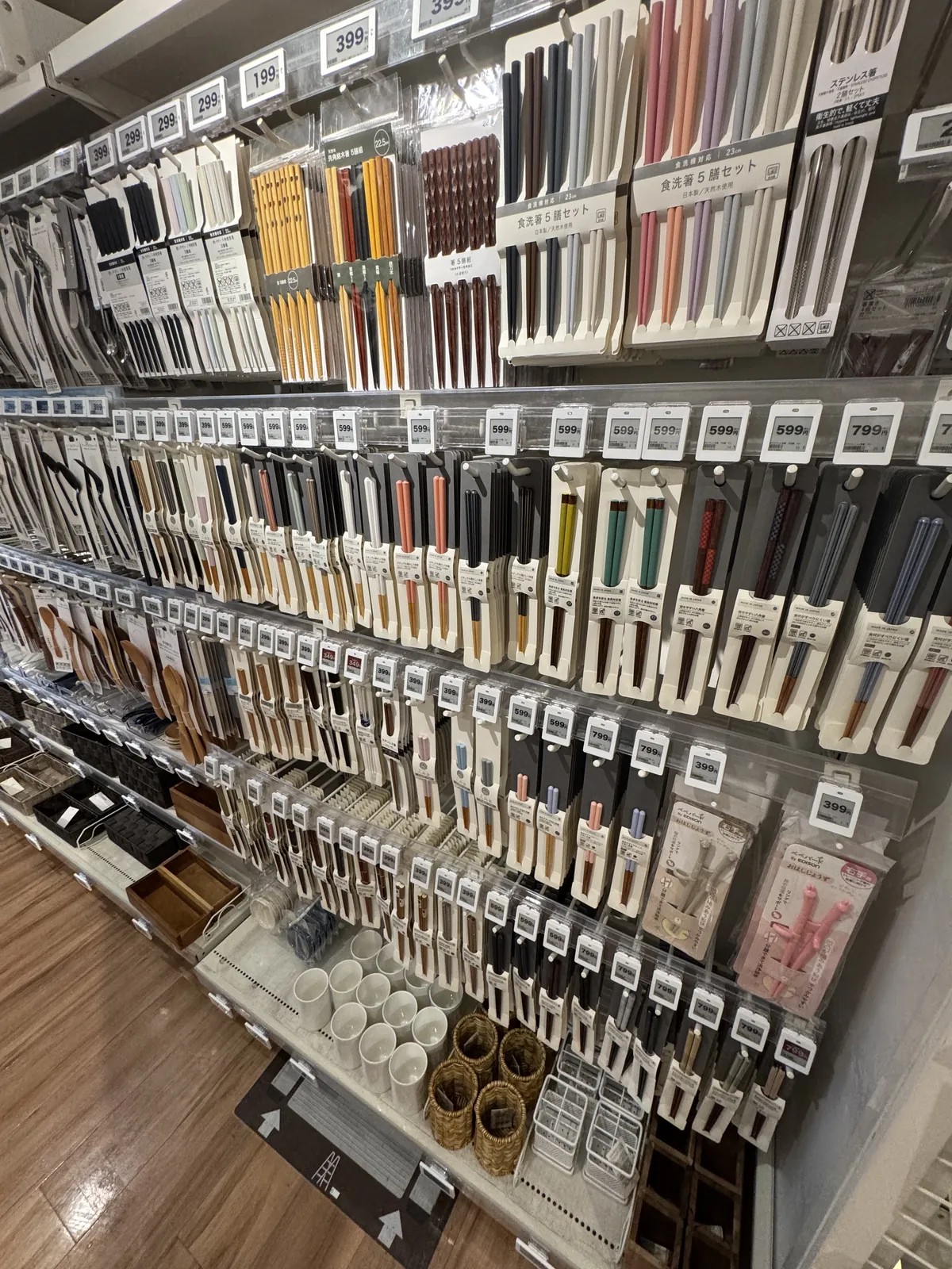 筷子卖场的墙面。装在袋子里的筷子挂成好几排,上层有几双一组的筷子套装。下层有筷子筒和木托盘。