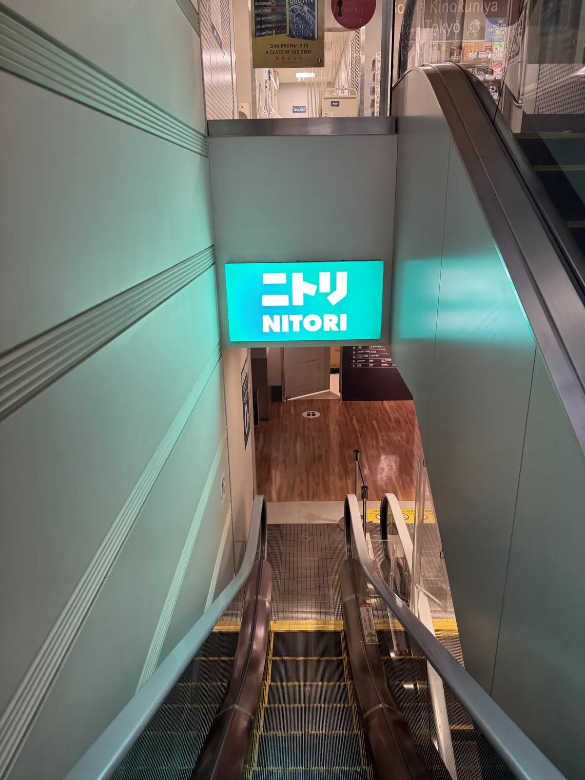 通往下一层的自动扶梯。下去后的墙上,有绿底白字、用日文和拉丁字母写着“NITORI”的招牌。