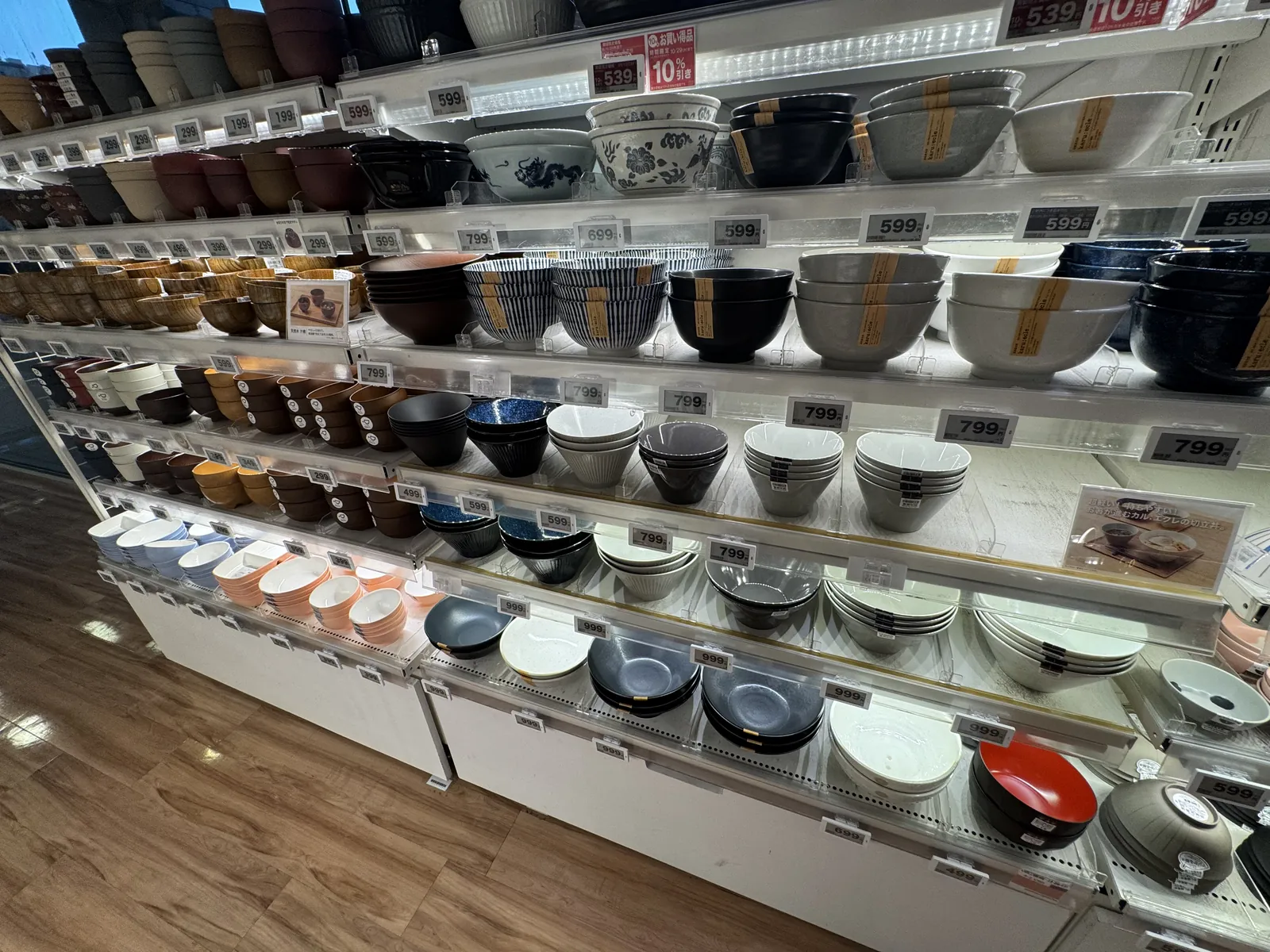 盖饭碗和钵的货架。棕色、藏青色、白色、灰色的器皿摆放在好几层货架上,货架上贴有价签。