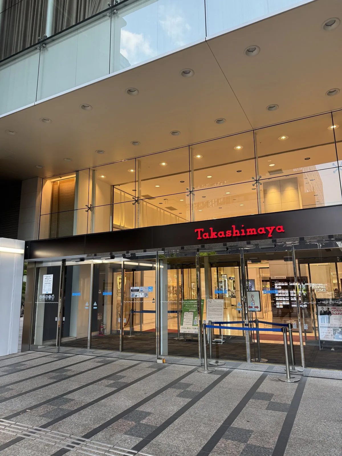 Ingresso esterno di Takashimaya Shinjuku. Sopra le porte di vetro c'è un'insegna con la scritta «Takashimaya» in lettere rosse.