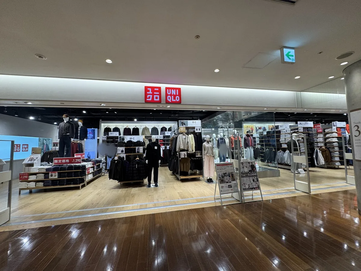 Ingresso di UNIQLO al 12F. Sotto l'insegna rossa sono allineati scaffali di abbigliamento e manichini.